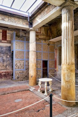 Ziyaretçiler Pompeii, İtalya 'daki antik bir Roma binasının kalıntılarında yürüyorlar. Kalan sütunlar ve duvarlar şehrin geçmişini gösteriyor..