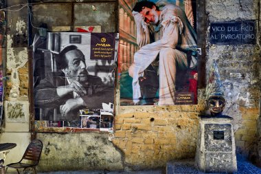 Street art in Vico del Fico al Purgatorio shows posters of Massimo Troisi and Peppino De Filippo. It highlights their legacy in Naples.