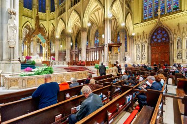 İnsanlar Manhattan, New York 'taki St. Patrick Katedrali' nde toplanıp dua ediyorlar. Sahne, tapınanları sessizce yansıtır..