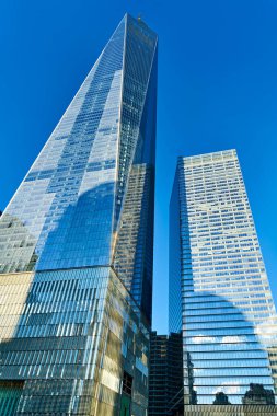 Manhattan 'da iki büyük bina duruyor. Bir Dünya Ticaret Merkezi mavi gökyüzüne ulaşır. Şehrin ufuk çizgisi modern mimariyi gösteriyor.