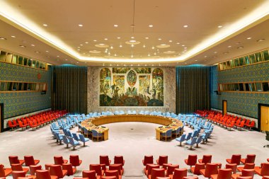 Güvenlik Konseyi Odasında sıra sıra renkli sandalyeler ve büyük bir duvar resmi var. Ayarlar küresel diplomaside önemli bir yeri yansıtıyor.