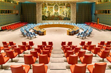 Ziyaretçiler Manhattan 'daki Birleşmiş Milletler Güvenlik Konseyi Odasını araştırıyorlar. Kırmızı ve mavi koltuklar odadaki merkezi masayı kuşatır..