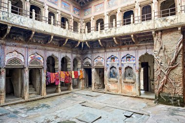 Ziyaretçiler, Mandawa Shekhawati, Rajasthan 'daki süslü boyanmış evleri ve kuru giysileri görüyorlar. Sanat çalışmaları yerel kültür ve geleneği yansıtıyor.