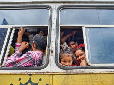 Birkaç yolcu Udaipur, Rajasthan 'da bir otobüsün içinde görüldü. Yetişkinler yakınlarda otururken bir çocuk gözetliyor..