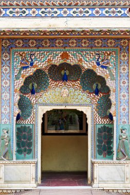 Ziyaretçiler, Jaipur, Rajasthan 'daki Şehir Sarayı' nda renkli tavus kuşu tasarımlarıyla ayrıntılı bir girişi keşfediyorlar. Tarihsel mimari birçok kişiyi cezbeder..