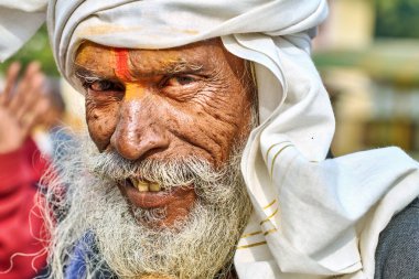 Uzun sakallı bir adam kameraya gülümsüyor. Gün boyunca Orchha, Madhya Pradesh 'te türban ve geleneksel kıyafetler giyer..