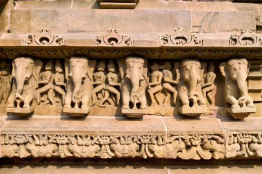 Ziyaretçiler, zengin tarihi sanat eserleri sergileyen Khajuraho, Madhya Pradesh 'teki tapınak duvarlarında fillerin ve insan figürlerinin ayrıntılı oymalarını görüyorlar..