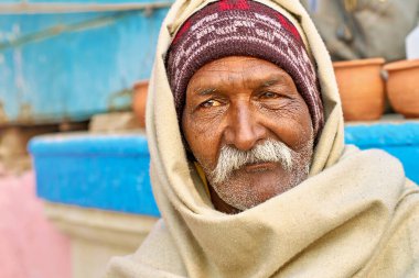 Varanasi, Uttar Pradesh 'te yaşlı bir adam sessizce oturuyor. Şal takıyor ve dikkatlice kameraya bakıyor..