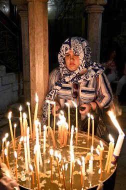 Bir ibadet eden Kudüs 'teki Kutsal Mezar Kilisesi' nde dini bir ziyaret sırasında mum yakar. Atmosfer bağlılığı ve inancı gösteriyor..