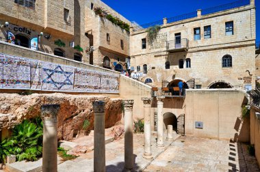 Ziyaretçiler, Roma sütunlarının antik yapılar ve tarih arasında yer aldığı Kudüs 'teki Yahudi mahallesini keşfediyorlar. İnsanlar açık alanda yürürler..