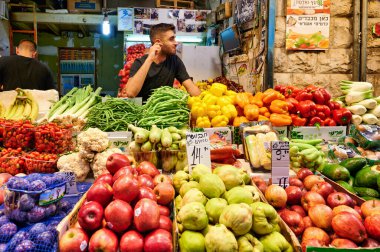 Müşteriler Kudüs 'teki Mahane Yehuda Pazarı' nı keşfediyorlar. Tedarikçiler yoğun bir atmosferde taze meyve ve sebze sunuyorlar..