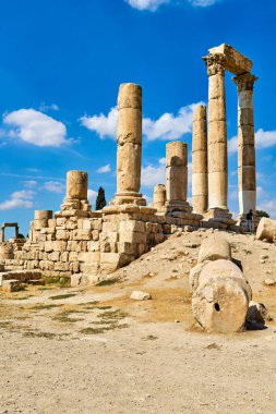 Ziyaretçiler Ürdün 'ün Amman kentindeki tarihi Hisar' ı keşfediyorlar. Sitede eski taş sütunlar ve parlak mavi bir gökyüzü altında kalıntılar yer alıyor..