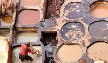 In Chouara Tannery, workers prepare animal hides in colorful dye pits under sunlight in Fez, Morocco during the day.