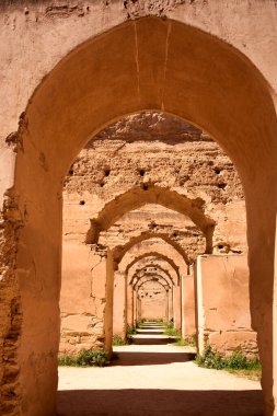 Ziyaretçiler Meknes Fas 'taki Kraliyet Ahırları' ndan geçerek eski kemerlere ve duvarlara hayranlıkla bakıyorlar. Ahırlar tarihi Fas mimarisini yansıtıyor.