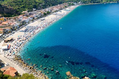 İnsanlar Scilla Calabria 'daki Marina Grande plajında yaz etkinliklerinin keyfini çıkarıyorlar. Mavi su ve kumlu plaj dinlenmek için birçok ziyaretçi çeker..