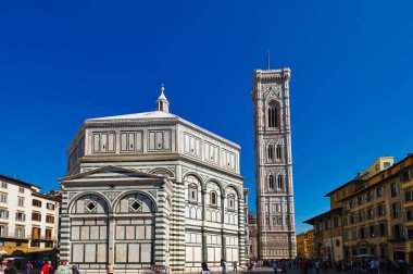 İnsanlar Floransa Toskana 'daki Baptistery ve Campanile' de dolaşıyorlar. Güneş açık mavi gökyüzünde parlıyor..