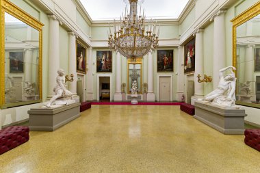 Konuklar Palazzo Pitti 'deki Palatine Galerisini geziyor. Odada büyük sanat eserleri, heykeller ve büyük bir avize bulunuyor..