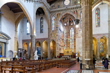 Santa Croce Bazilikası 'nın içinde insanlar sütunlar ve sanat eserleri arasında yürürler. Güneş ışığı vitray pencerelerden girer..