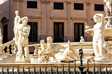 Ziyaretçiler, tarihi binalarla çevrili Piazza Pretoria çeşmesindeki heykellere hayran. Güneş Palermo 'nun bu canlı noktasında parlıyor..