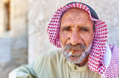 Halep, Suriye 'de oturan son sınıf öğrencisi, geleneksel kıyafetler giyiyor ve sigara içerken kırmızı beyaz bir eşarp takıyor..