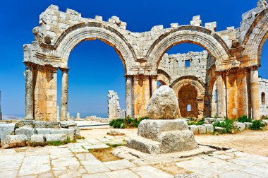 Suriye 'deki Aziz Simeon Stylites Kilisesi' nde eski taş kemerler bulunur ve açık mavi gökyüzü altında kalır. Tarihi bir yer olarak duruyor..
