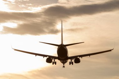 İniş takımlarıyla gün batımında uçan uçak. Arkadan görünen bir uçak. Seyahat kavramı.