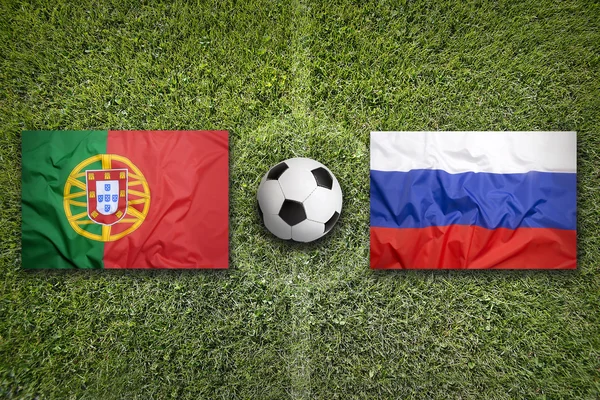 Прапори Португалії проти Росії на футбольному полі — стокове фото
