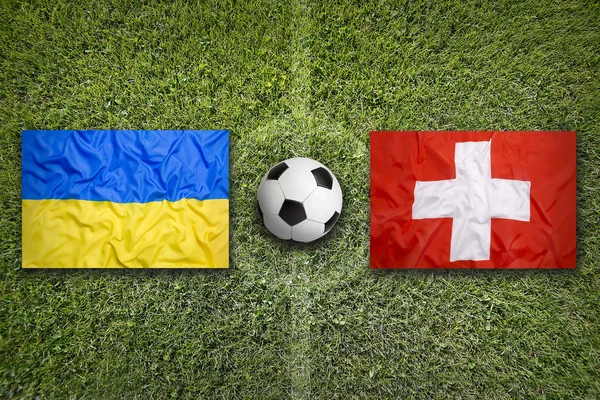 Ukraine vs. Switzerland flags on soccer field — Stock Photo, Image