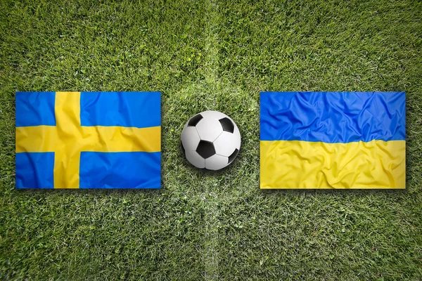 Sweden vs. Ukraine flags on soccer field — Stock Photo, Image