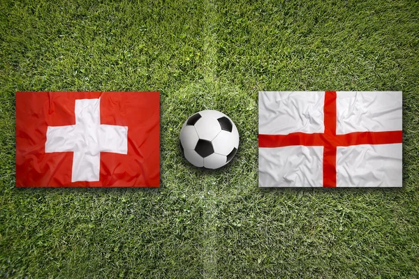 Швейцарія проти Англії прапори на футбольному полі — стокове фото