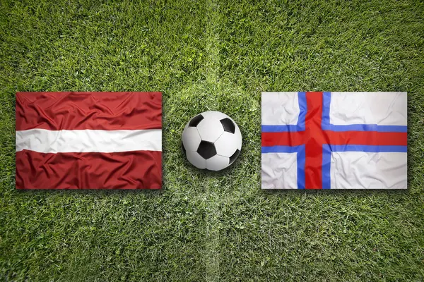 Латвія і Фарерські острови прапори на футбольному полі — стокове фото