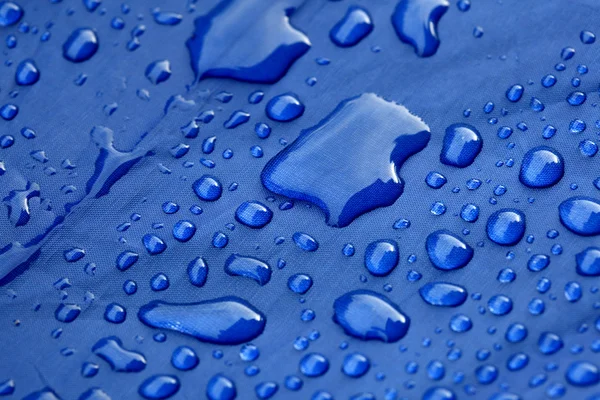 Primo piano di gocce di pioggia su un ombrello blu — Foto Stock