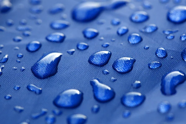 Fechar de gotas de chuva em um guarda-chuva azul — Fotografia de Stock