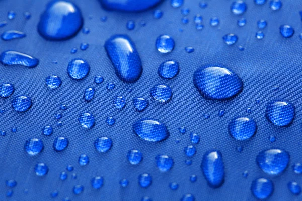 Fechar de gotas de chuva em um guarda-chuva azul — Fotografia de Stock