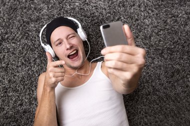 Attractive man with headphones makes selfie with his mobile clipart