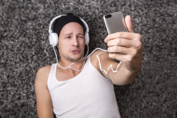 Hombre atractivo con auriculares infelices para hacer selfie con su m — Foto de Stock