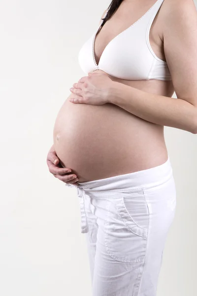 Zwangere vrouw voor een witte achtergrond — Stockfoto