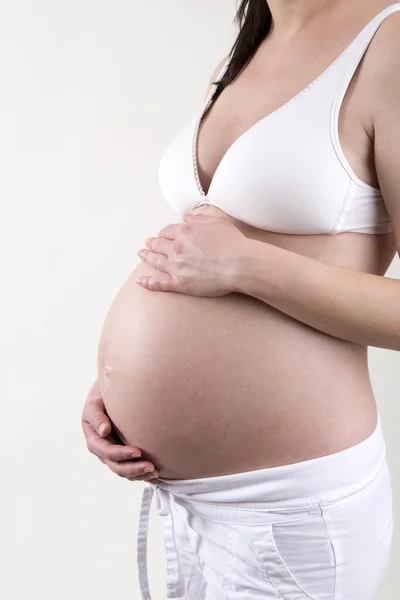 Zwangere vrouw voor een witte achtergrond — Stockfoto