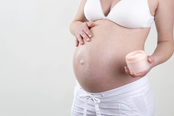 Mulher grávida colocando creme na barriga — Fotografia de Stock