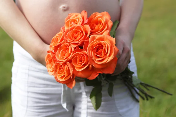 Mulher grávida ao ar livre com tulipas laranja em suas mãos — Fotografia de Stock