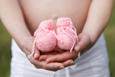 Hamile kadın açık pembe Bebek Patikleri elleri ile