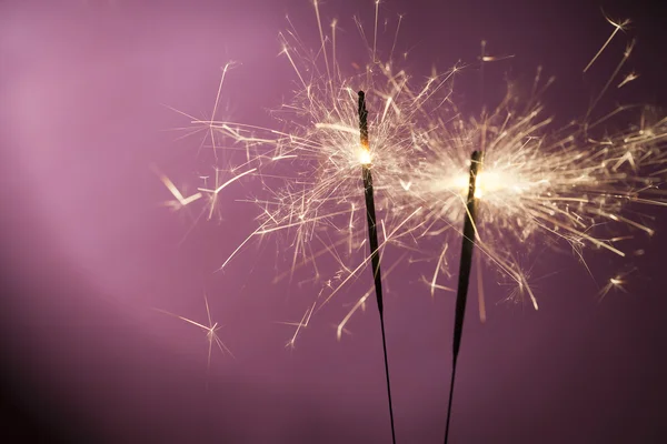 Burning sparklers on pink background — Stock Photo, Image