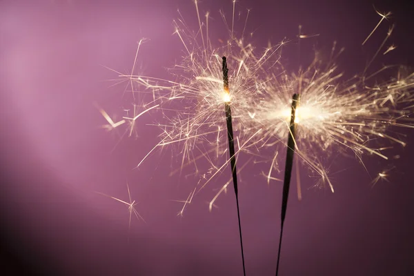 Brennende Wunderkerzen auf rosa Hintergrund — Stockfoto