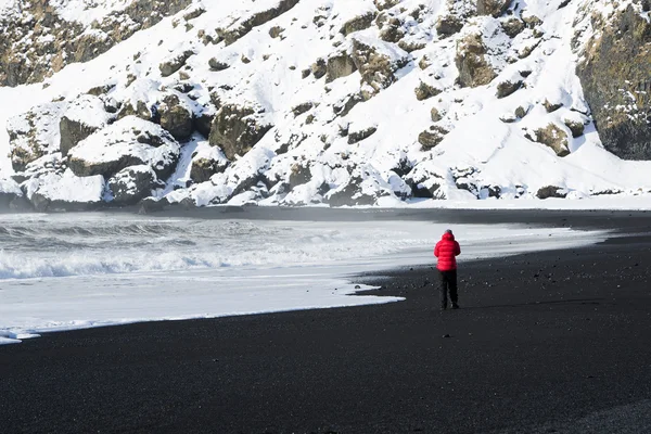 Woman walks along black sand beach in Vik, Iceland — Stock Photo, Image