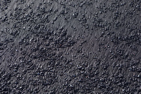 Stenen structuur op een zwarte zand strand — Stockfoto