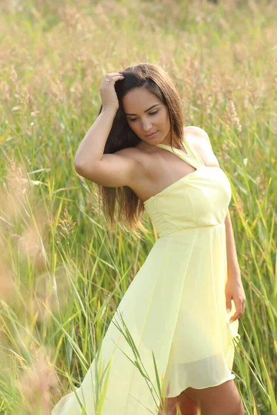 夏にポーズをとる黄色のドレスの若い美しい女性 — ストック写真