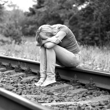 Kızgın yetişkin kadın raylarda oturuyor.