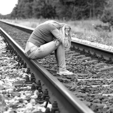 Kızgın yetişkin kadın raylarda oturuyor.