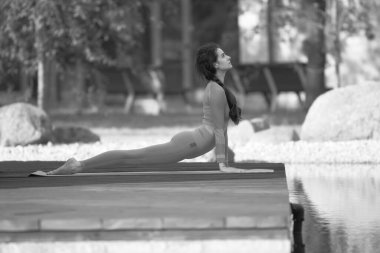 Yoga yapan güzel genç bir kadın, açık havada.