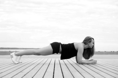 Genç atletik sağlıklı kız deniz kenarında yoga yapıyor.